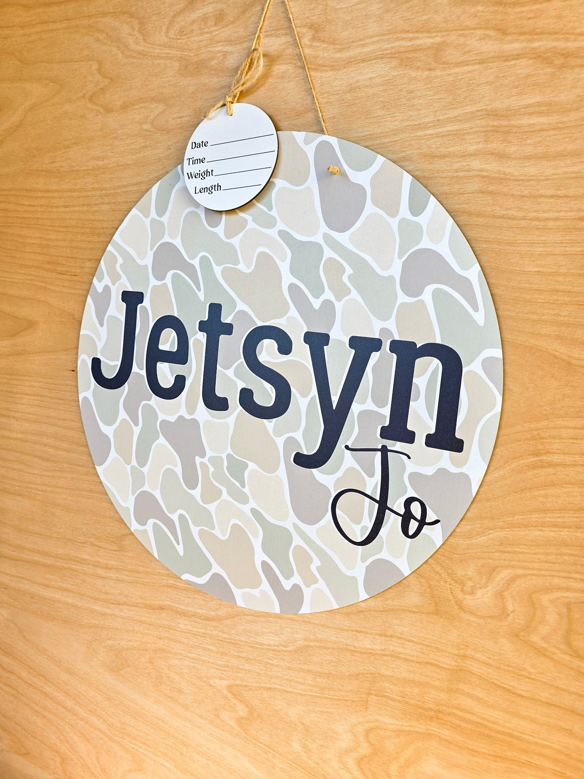 Bold black personalized baby name on round camouflage hospital door sign